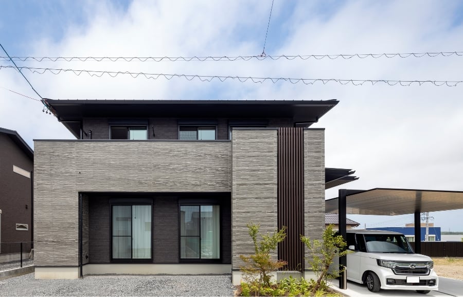 グレーの外壁に濃いブラウンの縦格子がアクセントの二階建て新築注文住宅の外観写真
