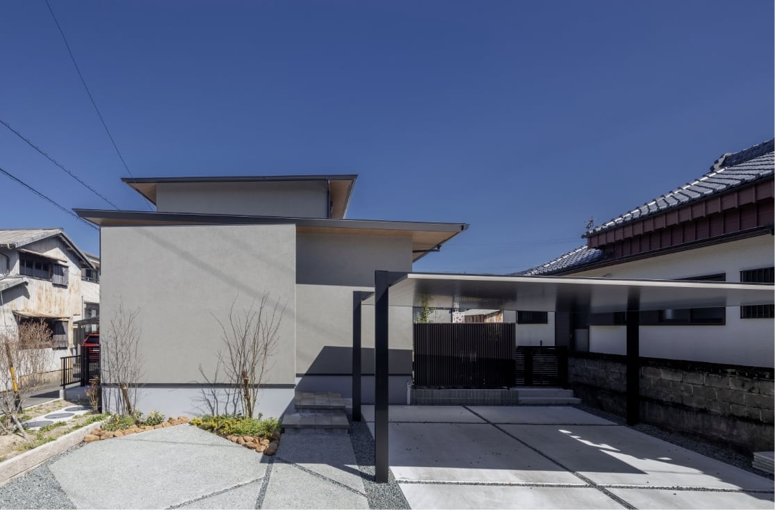 スタイリッシュなカーポートと広い駐車スペースがある塗り壁グレー外壁の二階建て新築注文住宅外観