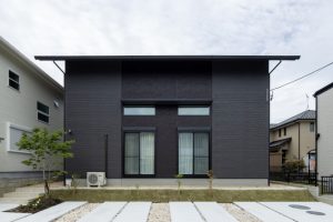 黒い外壁の窓がシンメトリーな二階建ての家